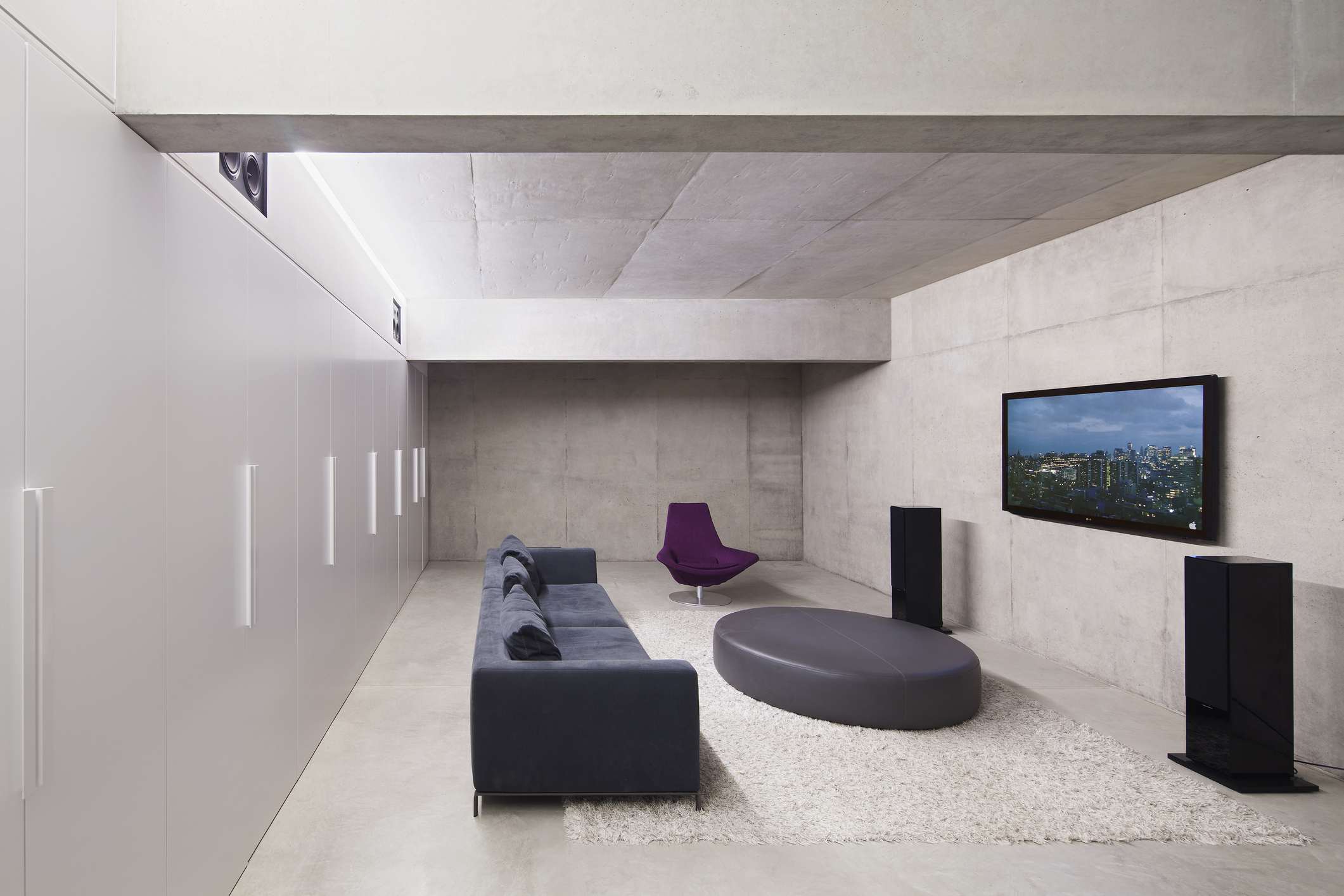 Modernt vardagsrum med väggmonterad TV, stereohögtalare och soffa