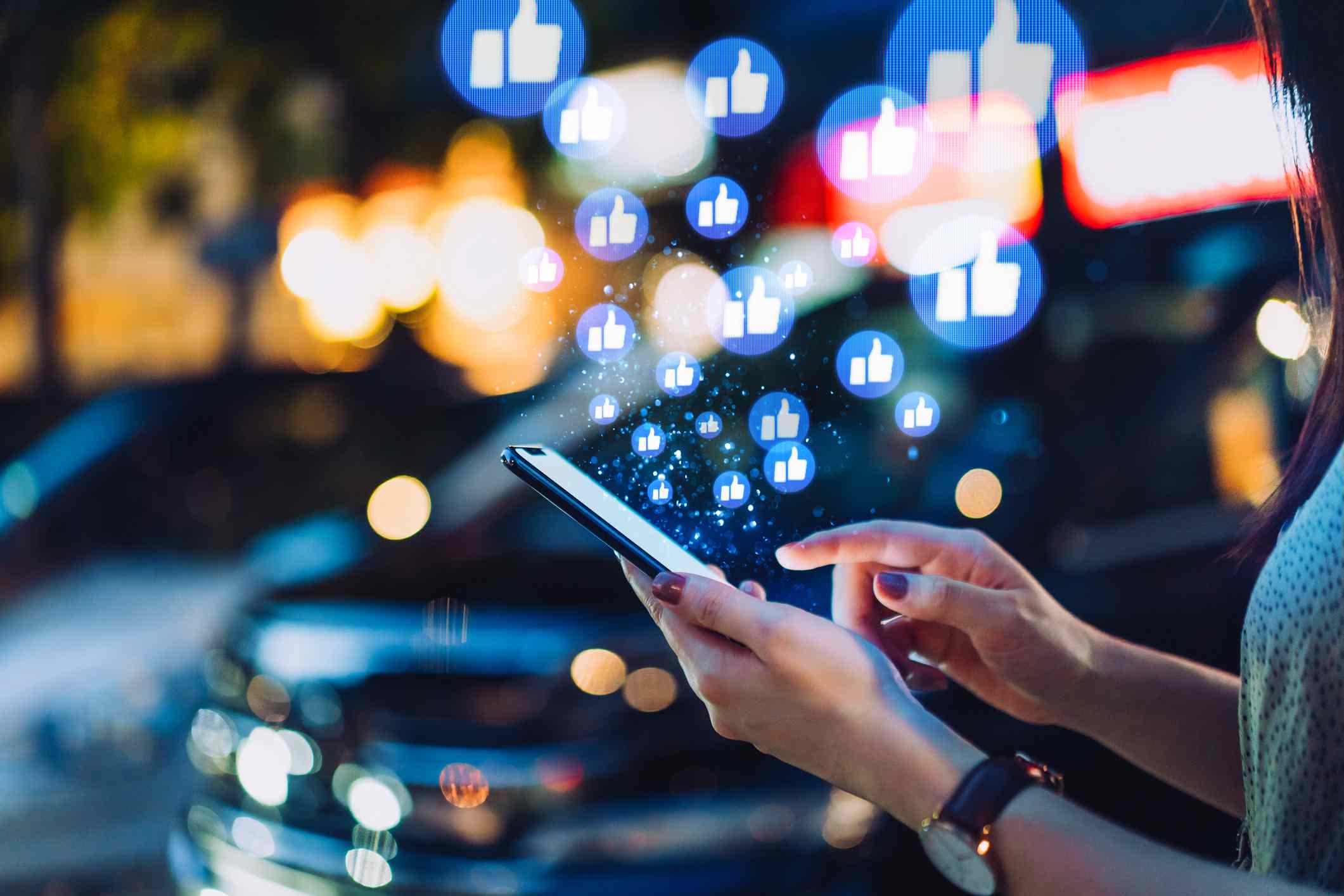 Någon som använder smartphone på sociala medier nätverksapplikationer på språng, visar eller ger gillar i staden på natten.