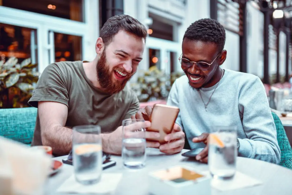 swedish male laughing while browsing social media with his african friend 1184006408 f206f254fbbf465183e0d72f183822c6