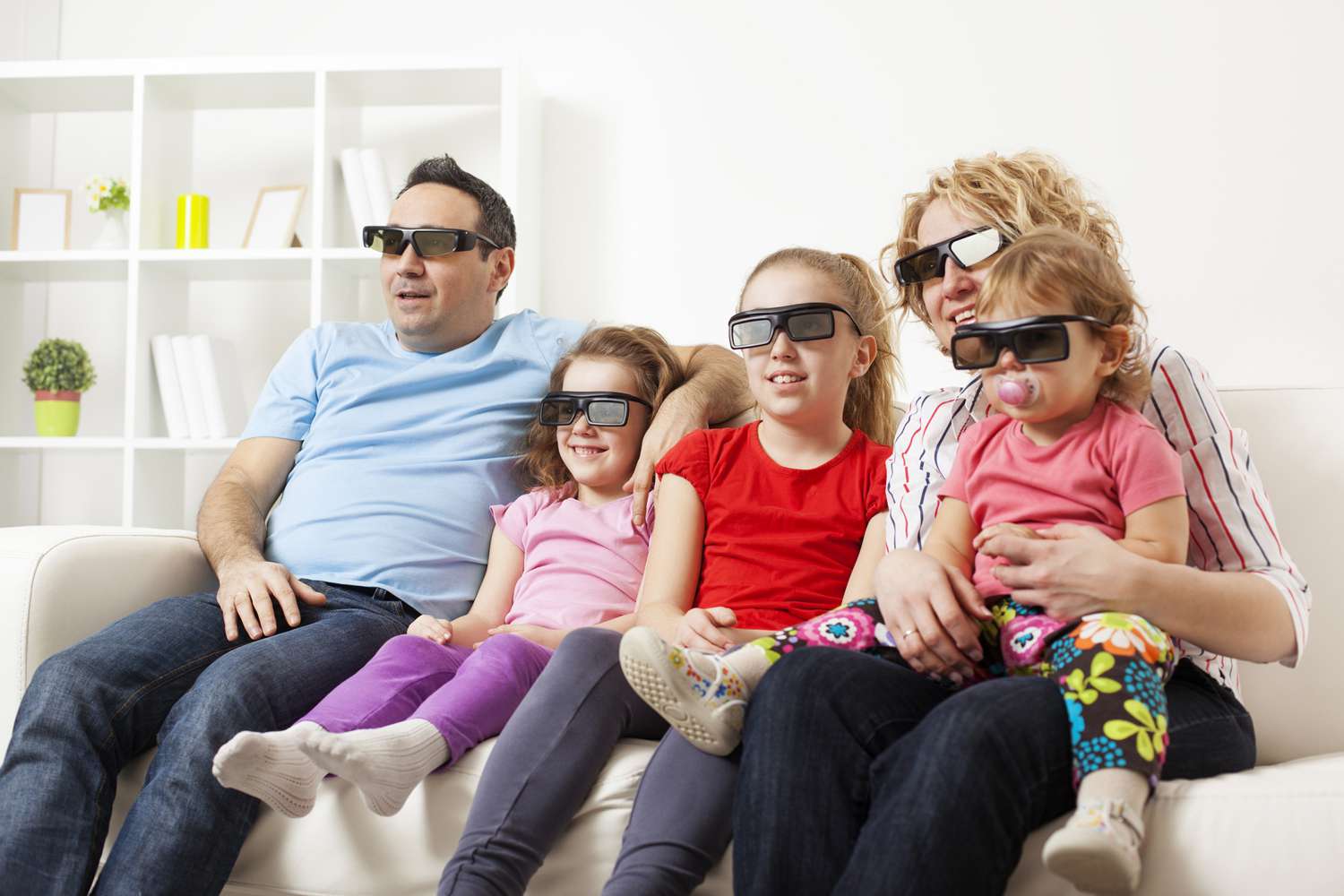Familj som tittar på TV med 3D-glasögon.