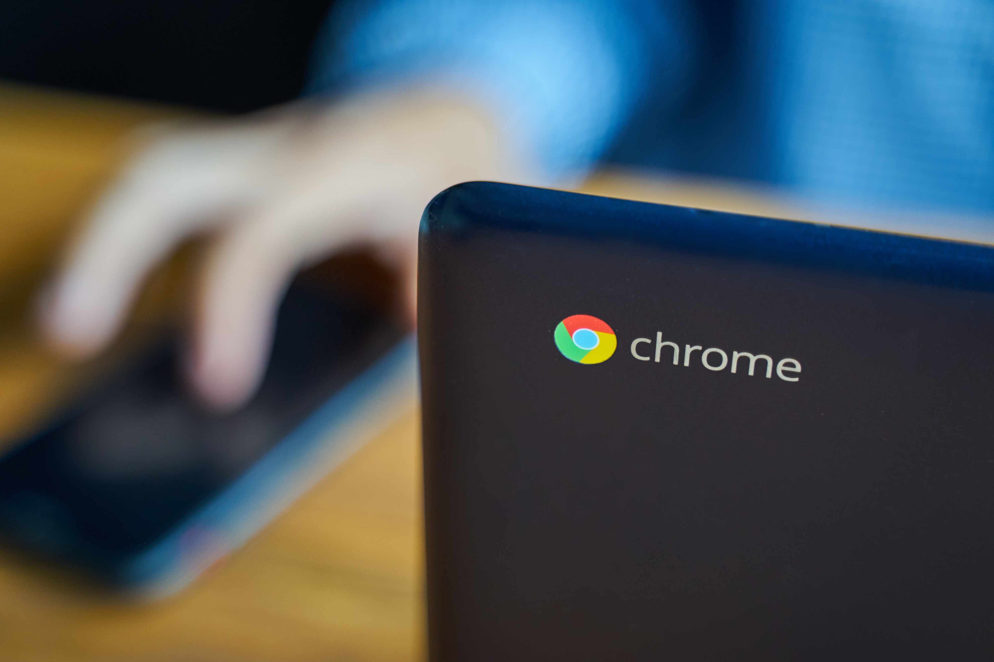 En Google Chromebook på ett skrivbord bredvid en person som använder en Android-telefon