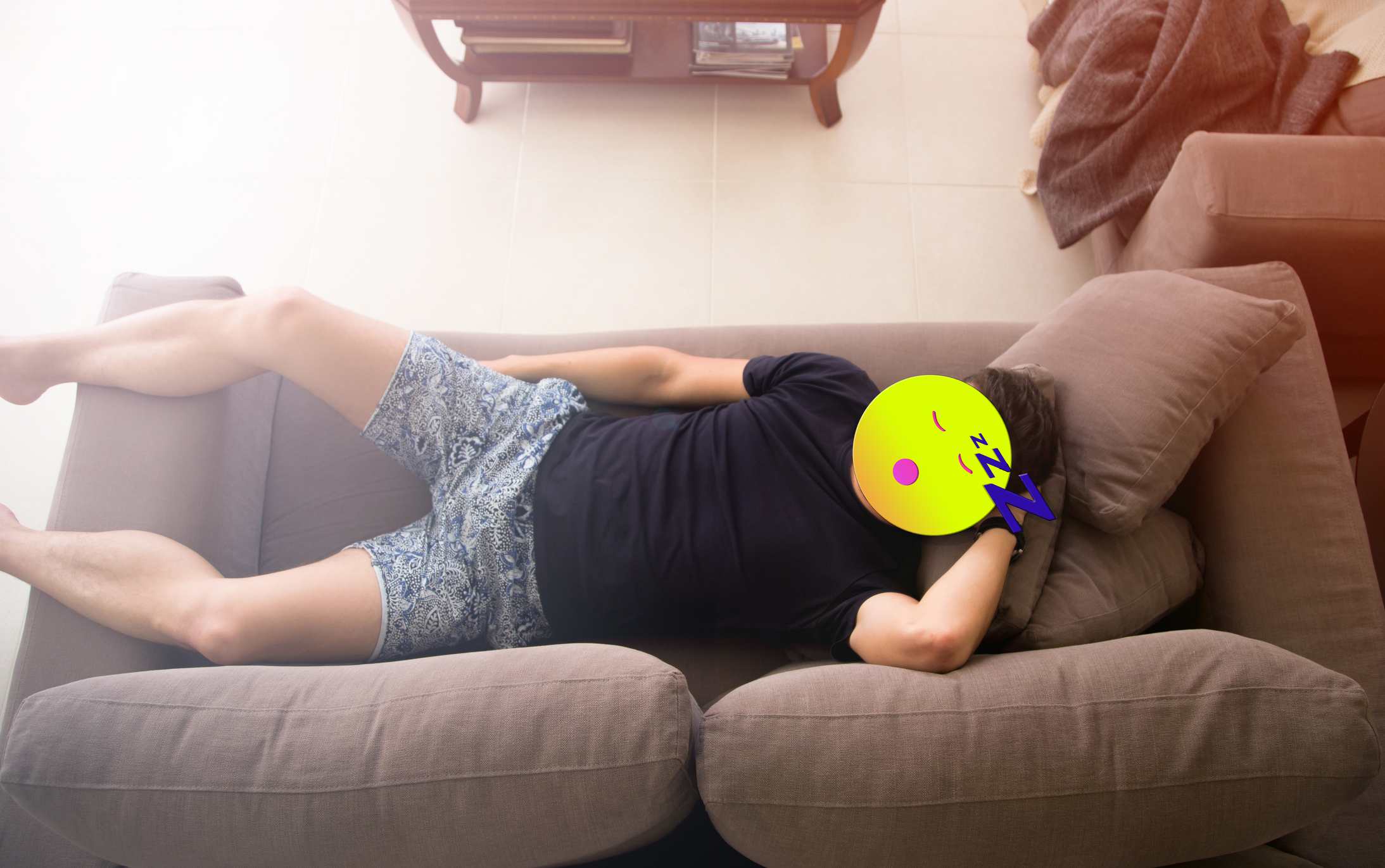 En man som ligger på en soffa med en emoji framför hans huvud