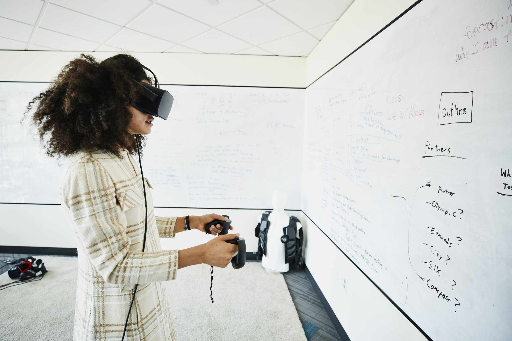 Någon som använder VR-skyddsglasögon och kontroller medan man tittar på en stor whiteboard.