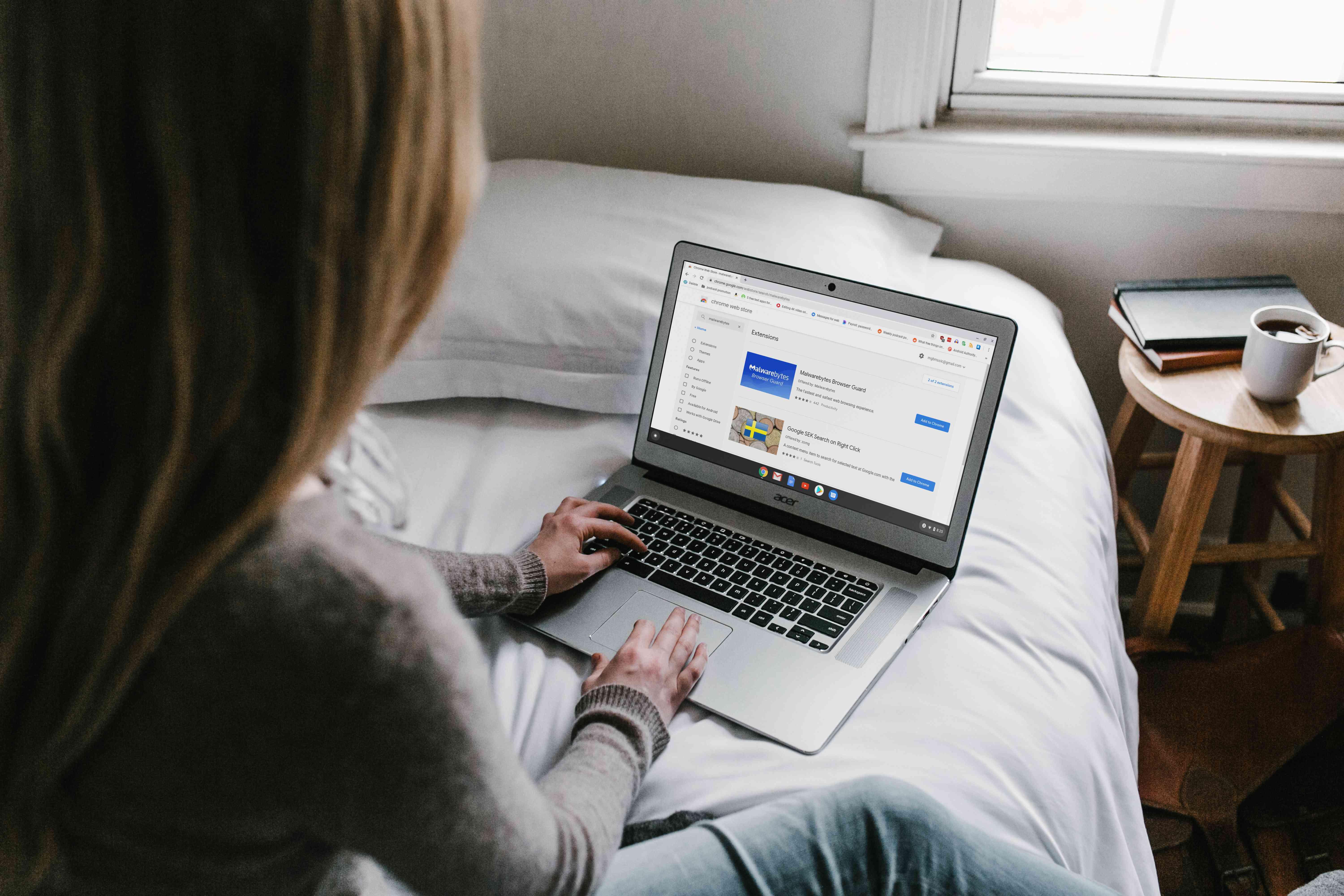 Kvinna som använder en bärbar dator på en säng