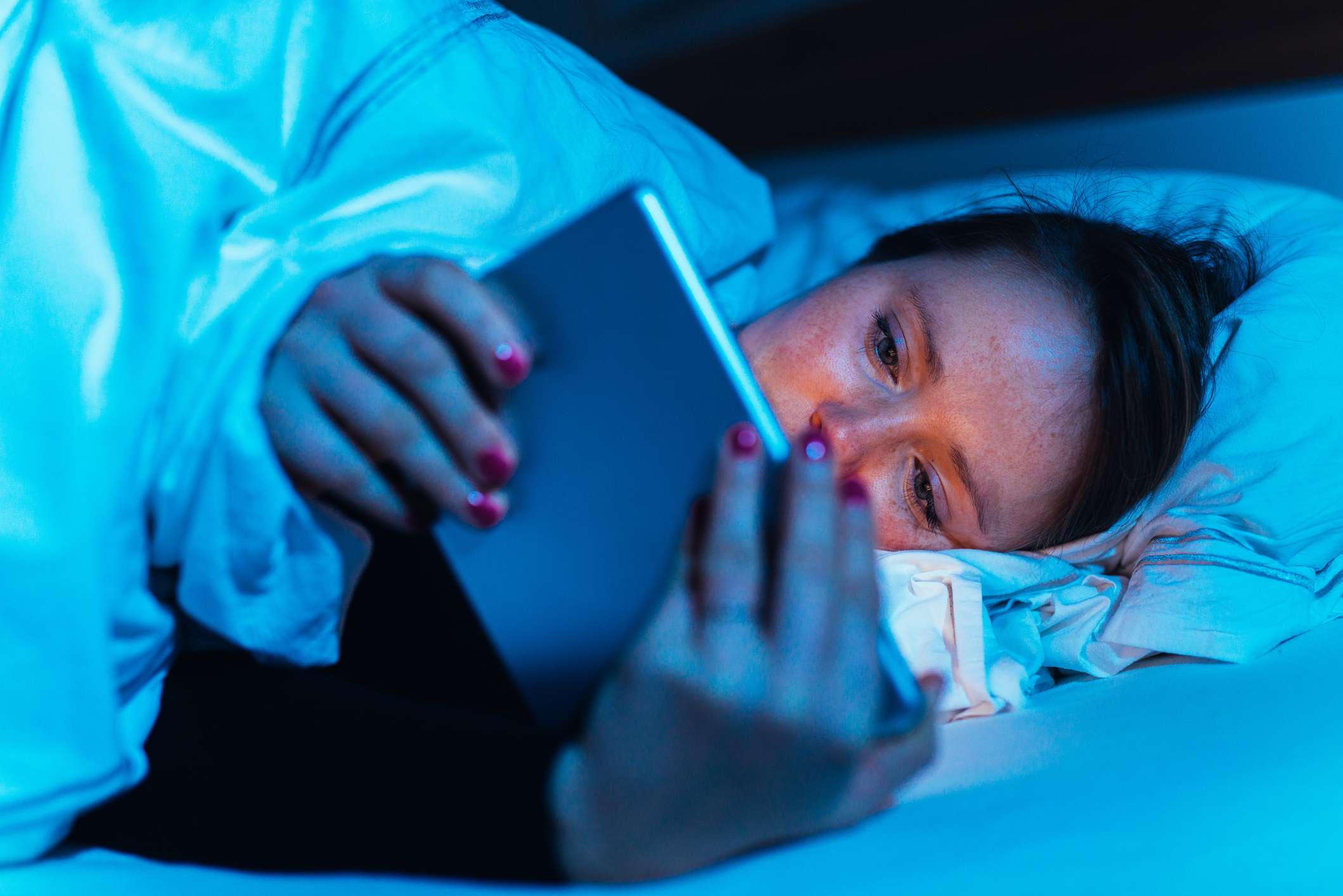kvinna som använder sin tablett i sängen på natten
