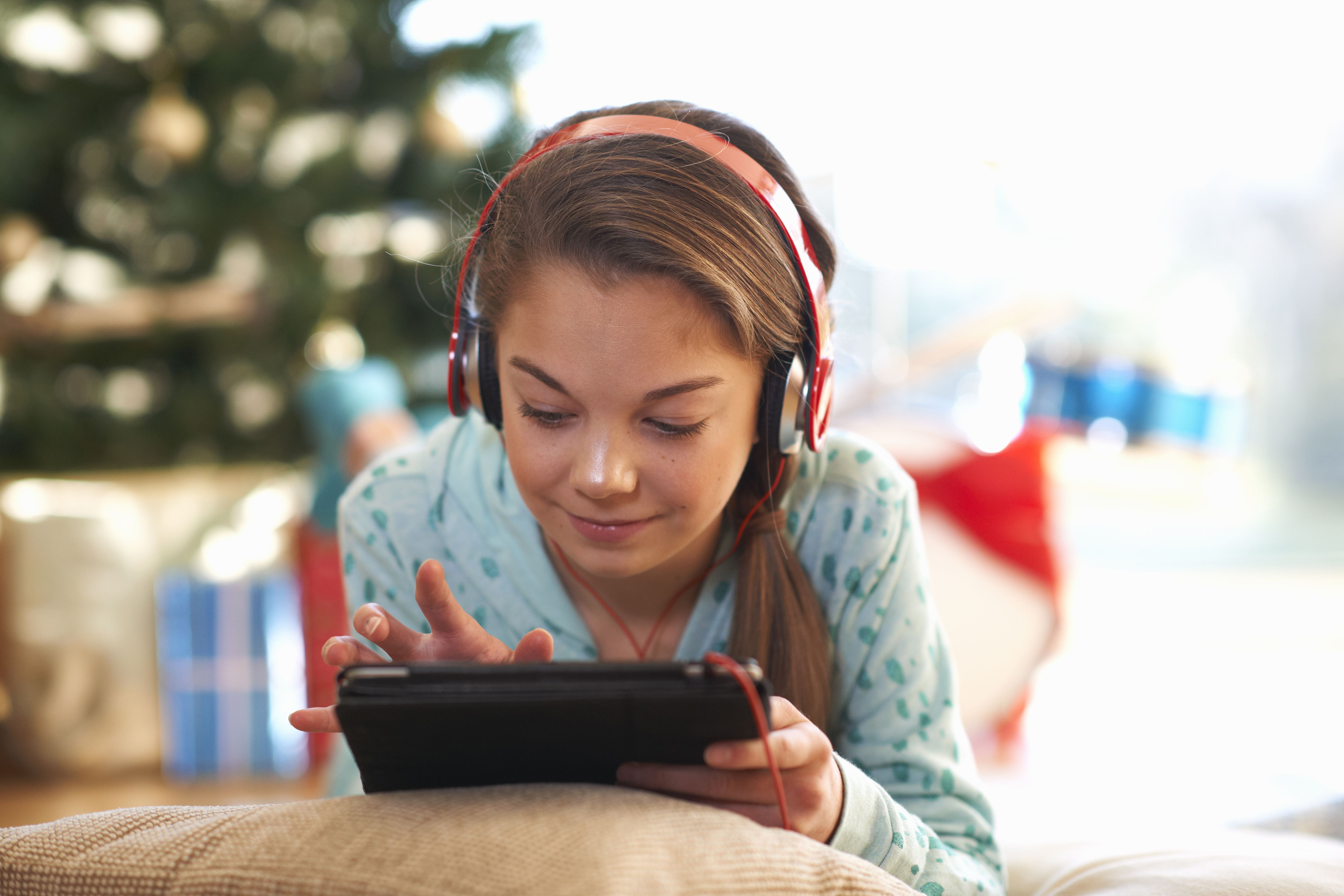 Flicka som ligger på vardagsrumsgolvet genom att använda den digitala minnestavlan pekskärm på jul