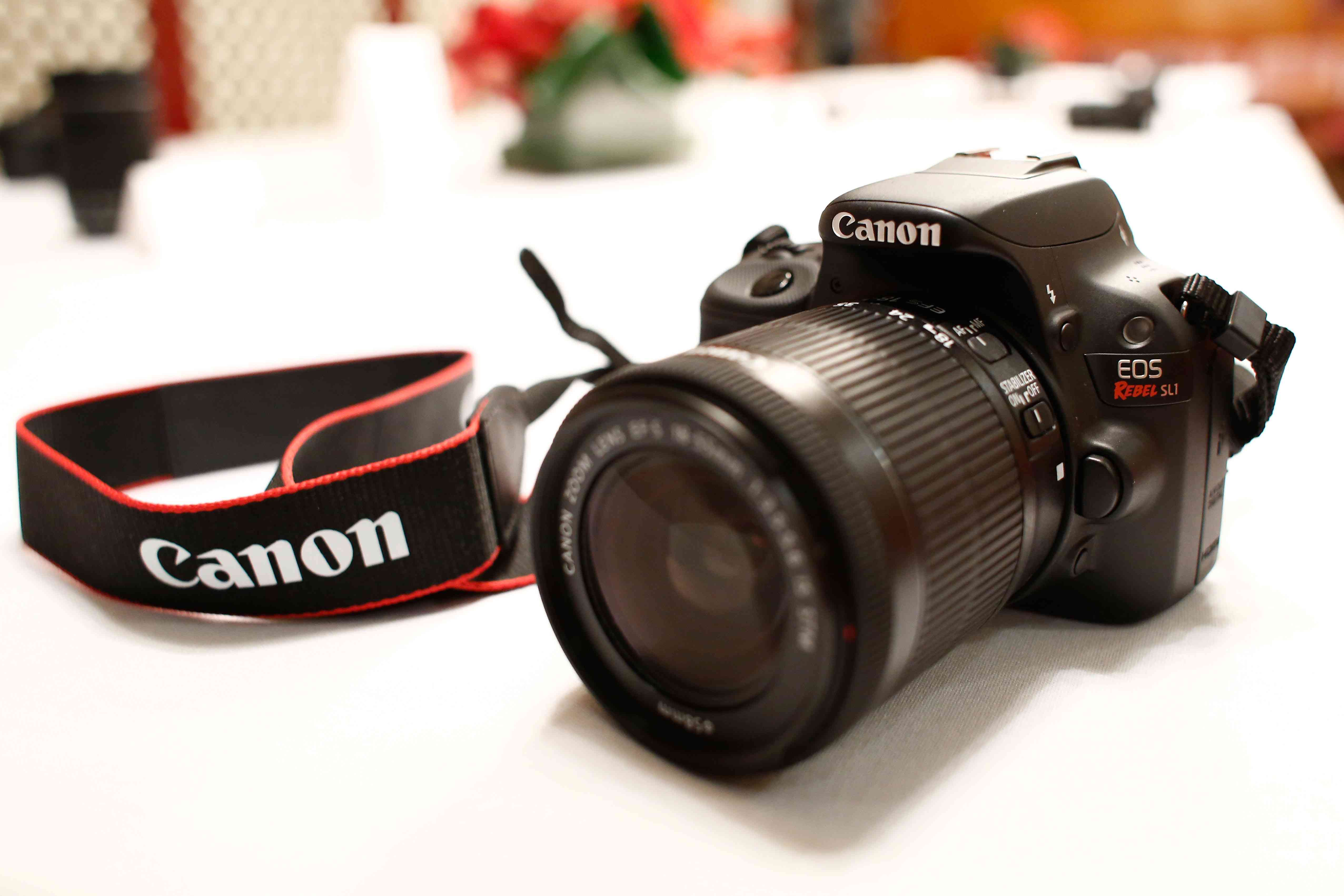 En Canon DSLR-kamera med rem på ett vitt bord