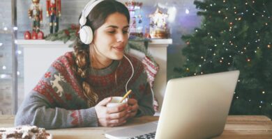 woman with cup of coffee using laptop and headphones at christmas time 681904577 59babded519de20010ea535e