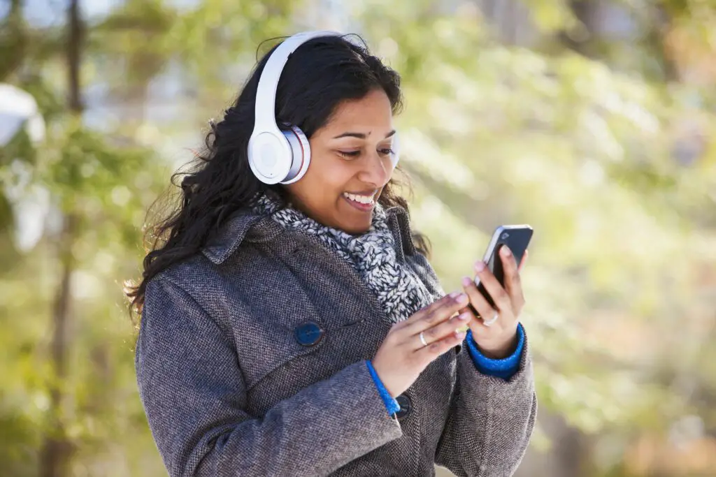 young woman of south asian ethnicity using cell phone and bluetooth headphones in scanlon creek conservation area 574897321 5aa1b50e18ba010037c50439