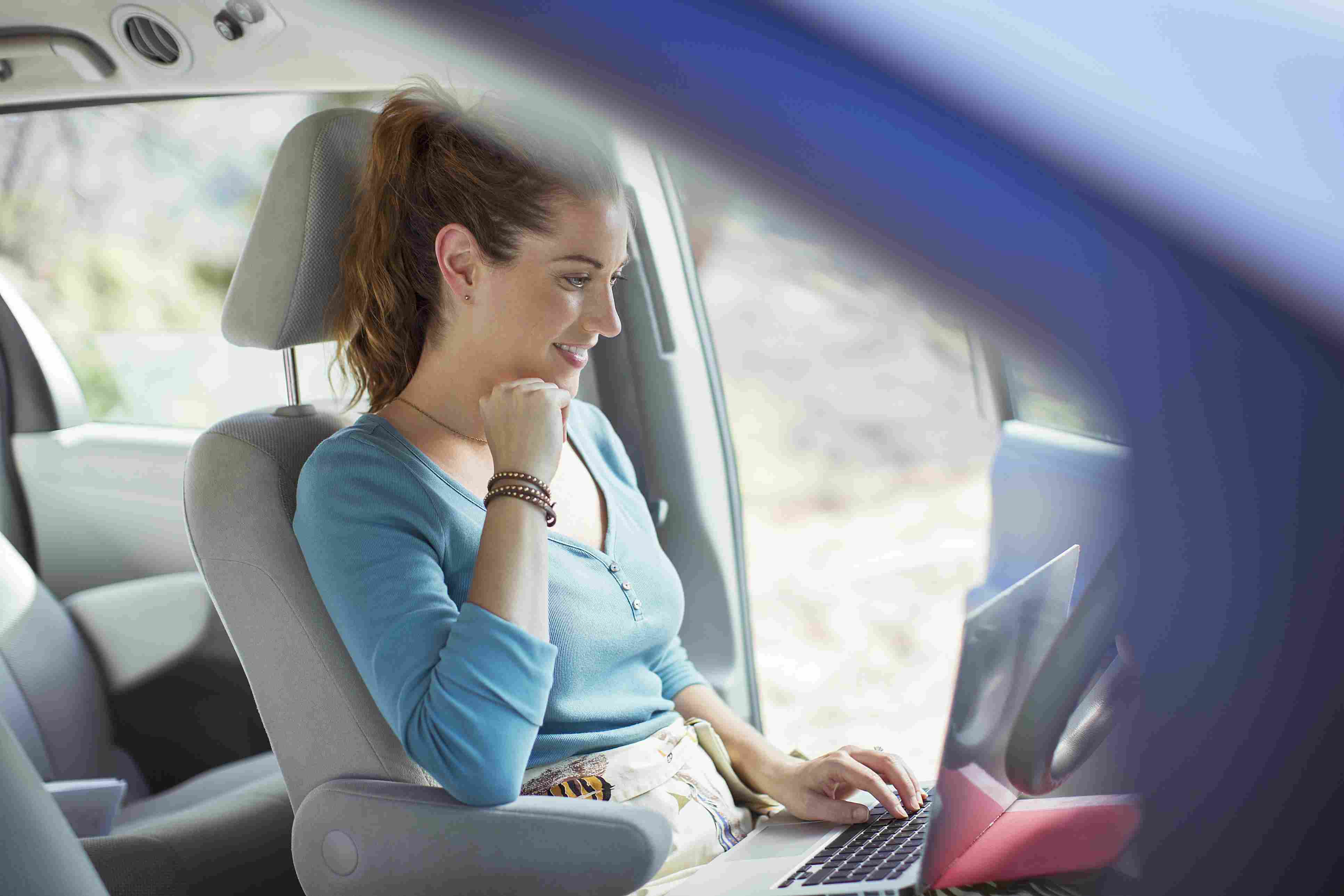 kvinna som använder bärbar dator i bil med wifi
