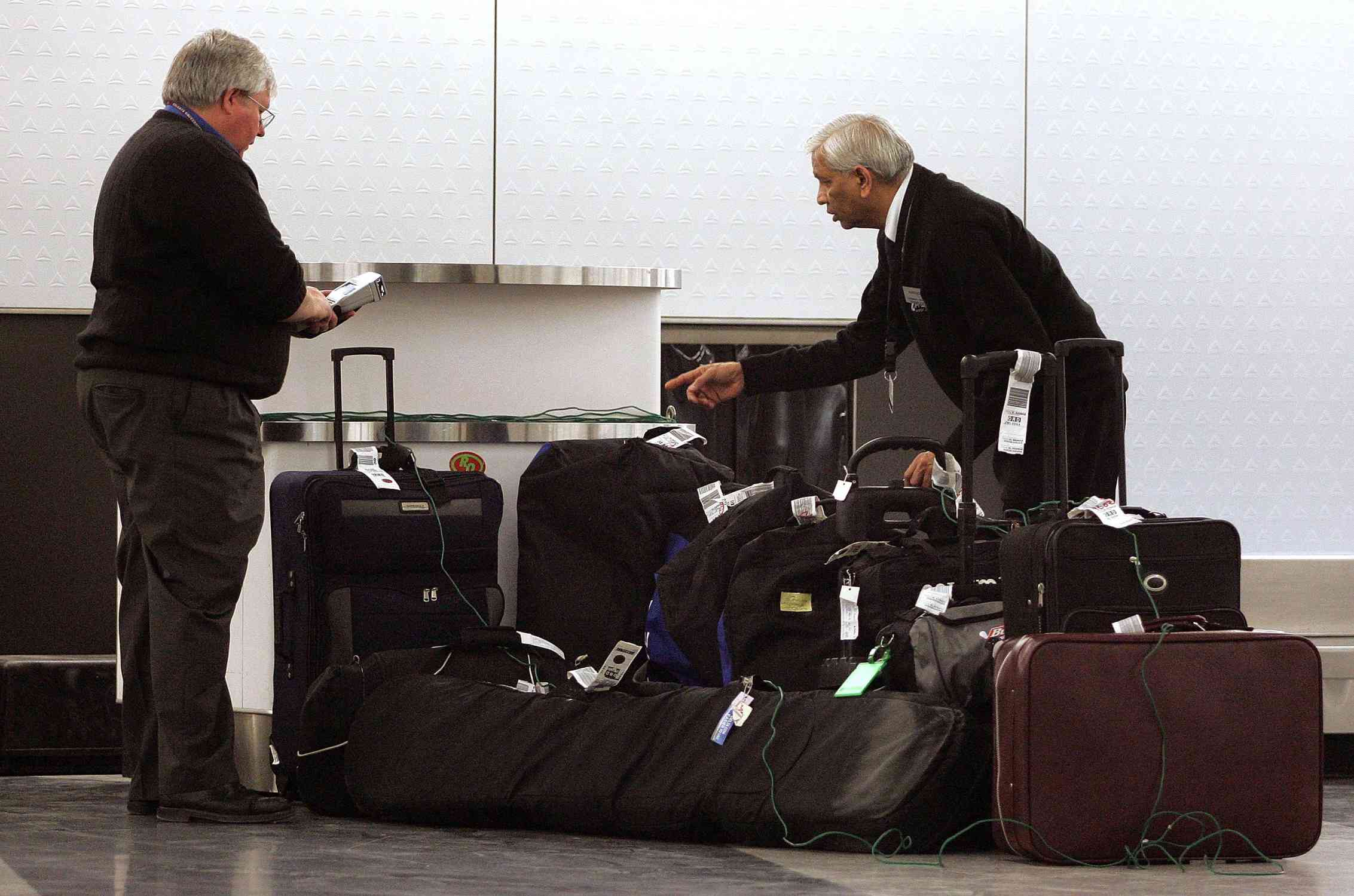 Två flygplatsanställda som kontrollerar en grupp bagage