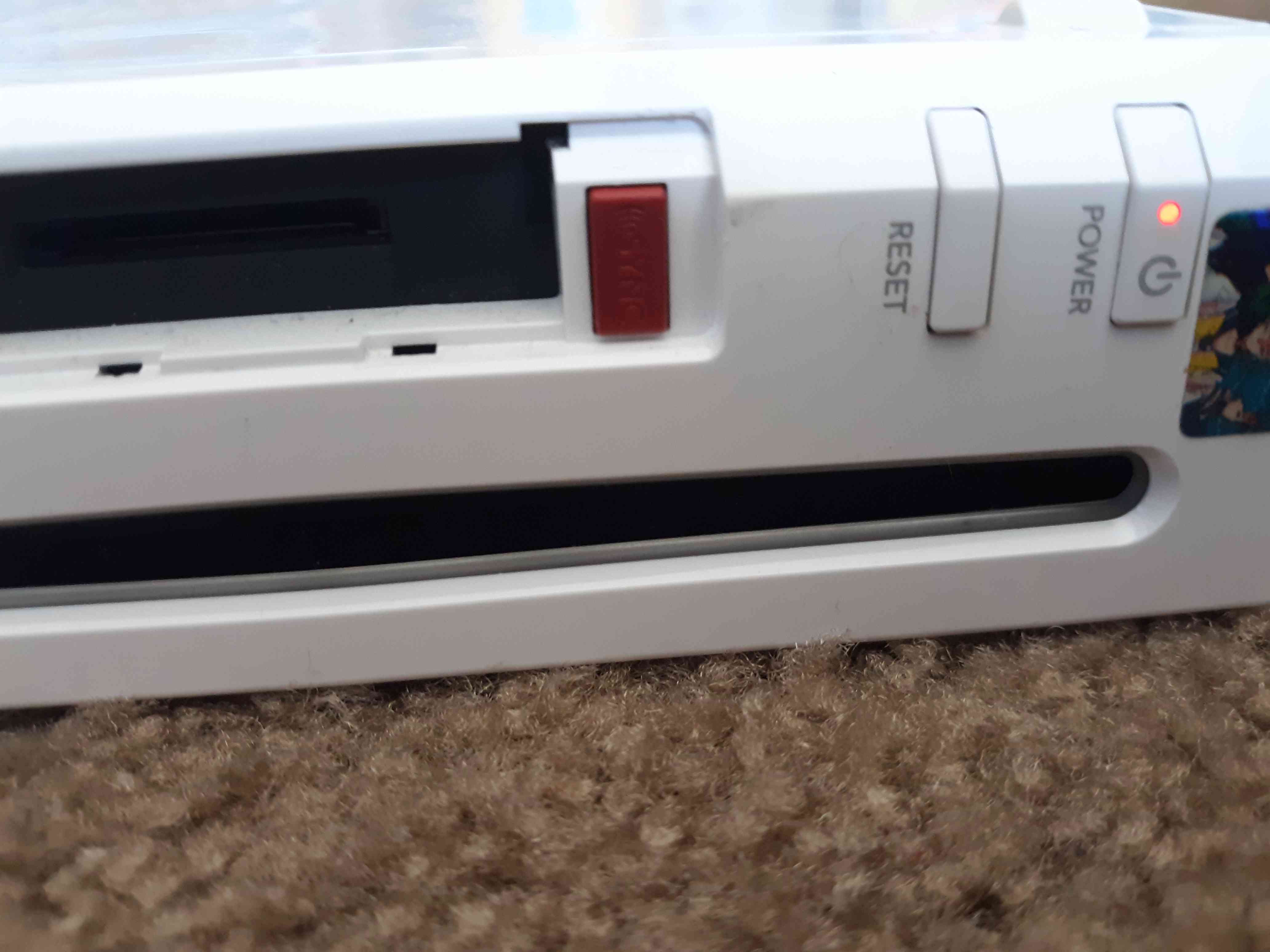 Den röda synkroniseringsknappen finns under minneskortsfackets lock på Wii-konsolens framsida.