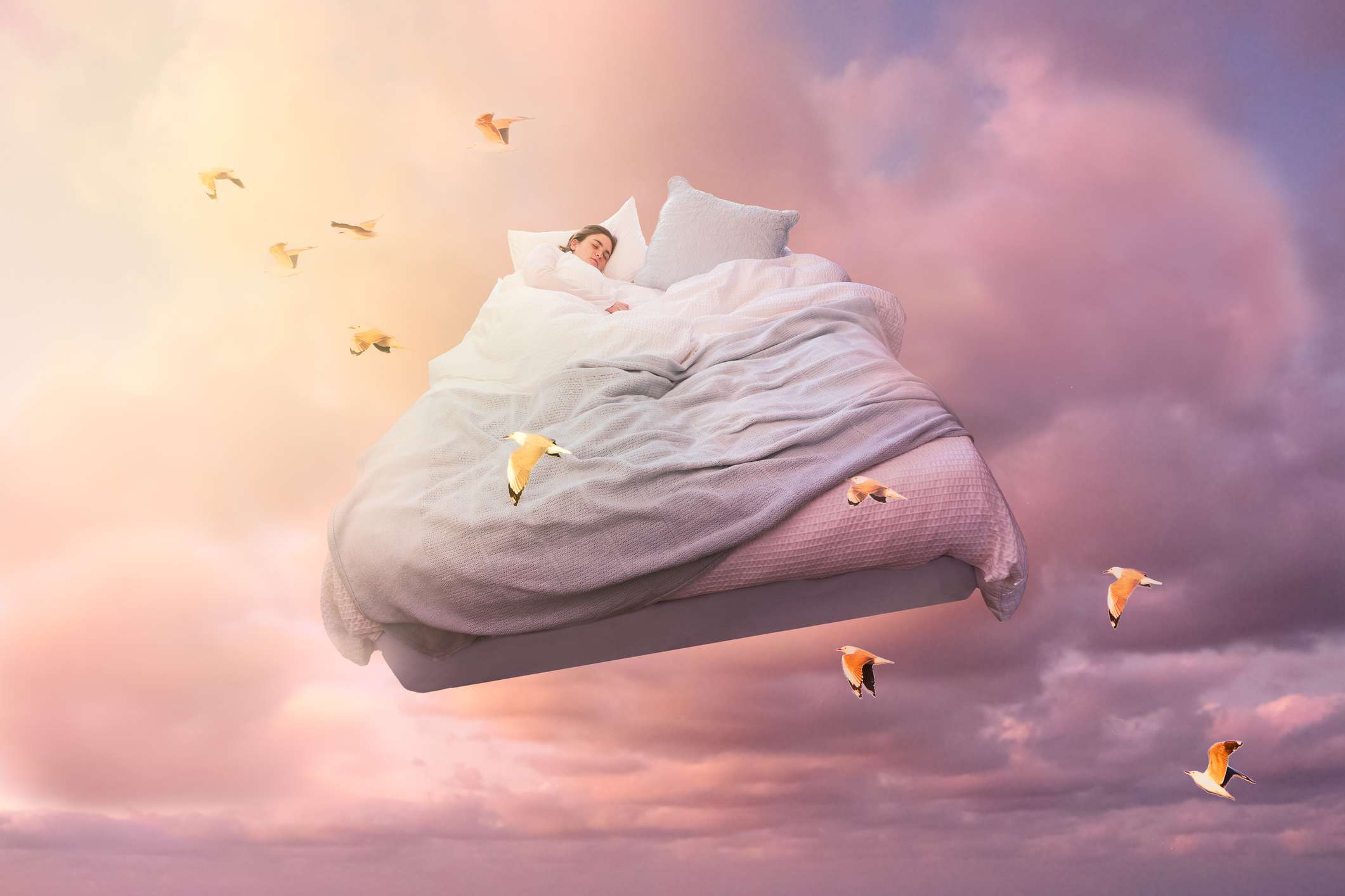 En sovande flicka flyter på en säng i himlen och drömmer