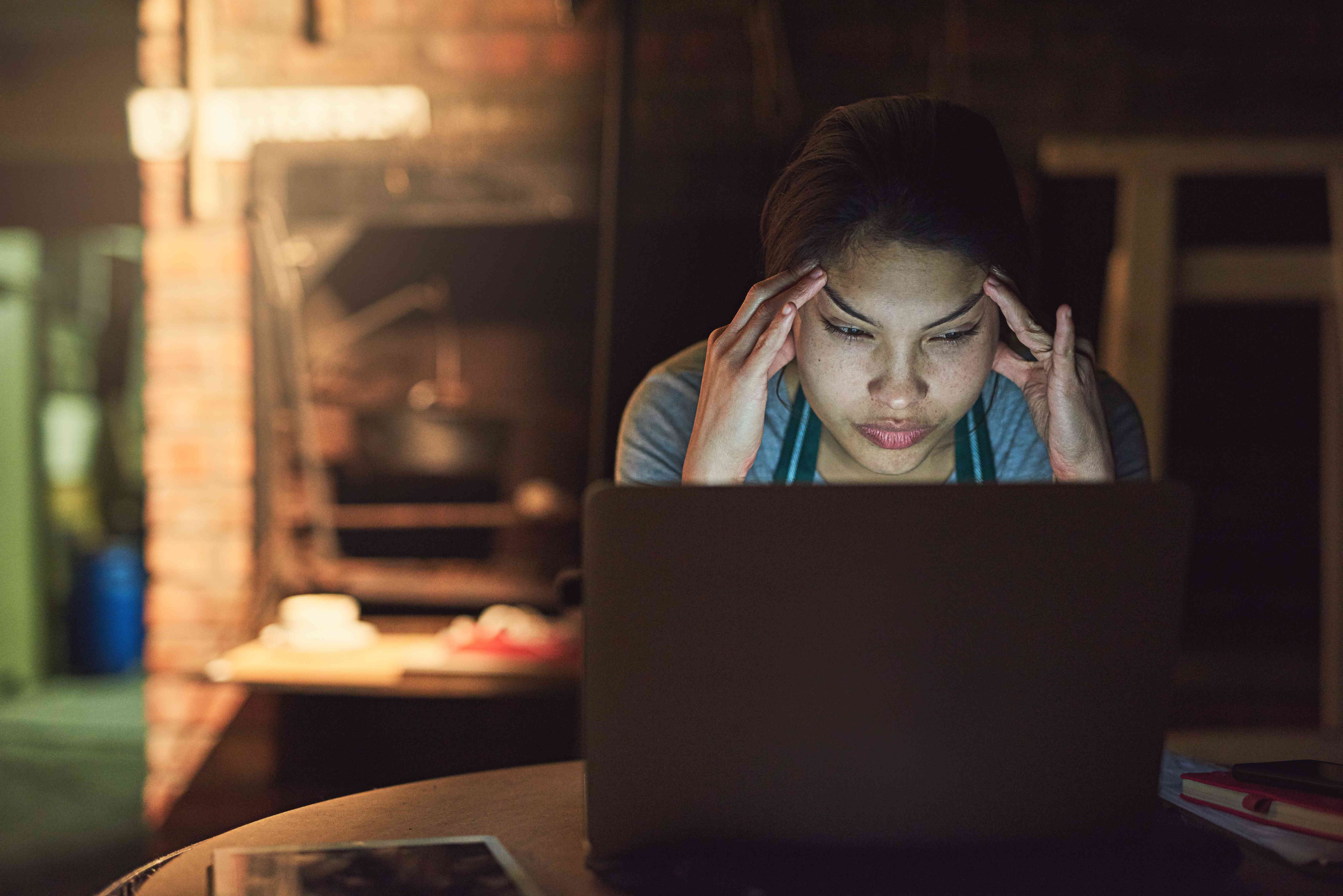 En kvinna med ett frustrerat ansiktsuttryck använder en bärbar dator.