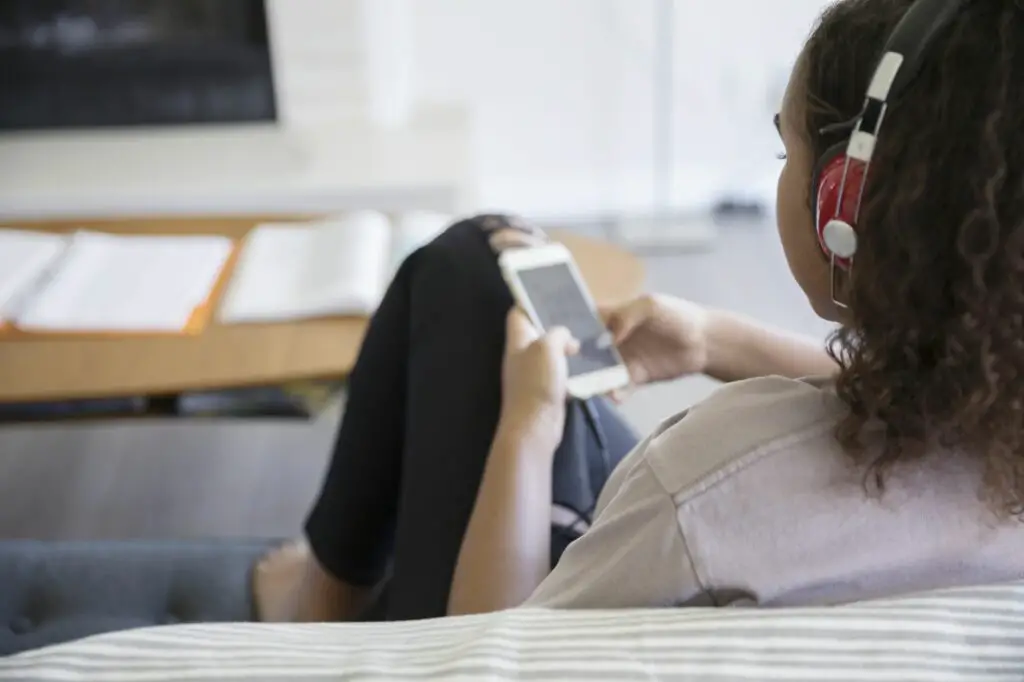 teenage girl listening to music with headphones and mp3 player on living room sofa 753287827 5a5c3e3296f7d00037d3f7e5