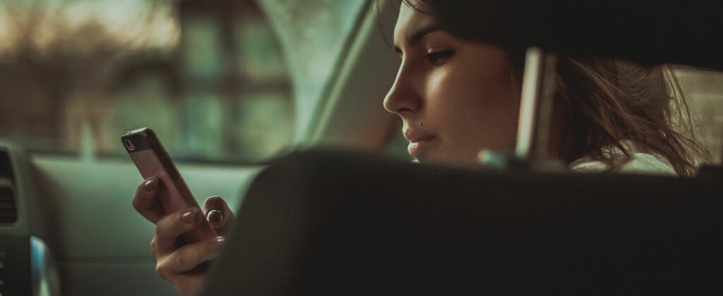 young woman holding smart phone in car 673447827 5bc7b3e84cedfd0051288908