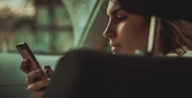 young woman holding smart phone in car 673447827 5bc7b3e84cedfd0051288908