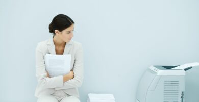 young woman in suit sitting next to printer 81737128 5b2afc9543a10300367c44f4