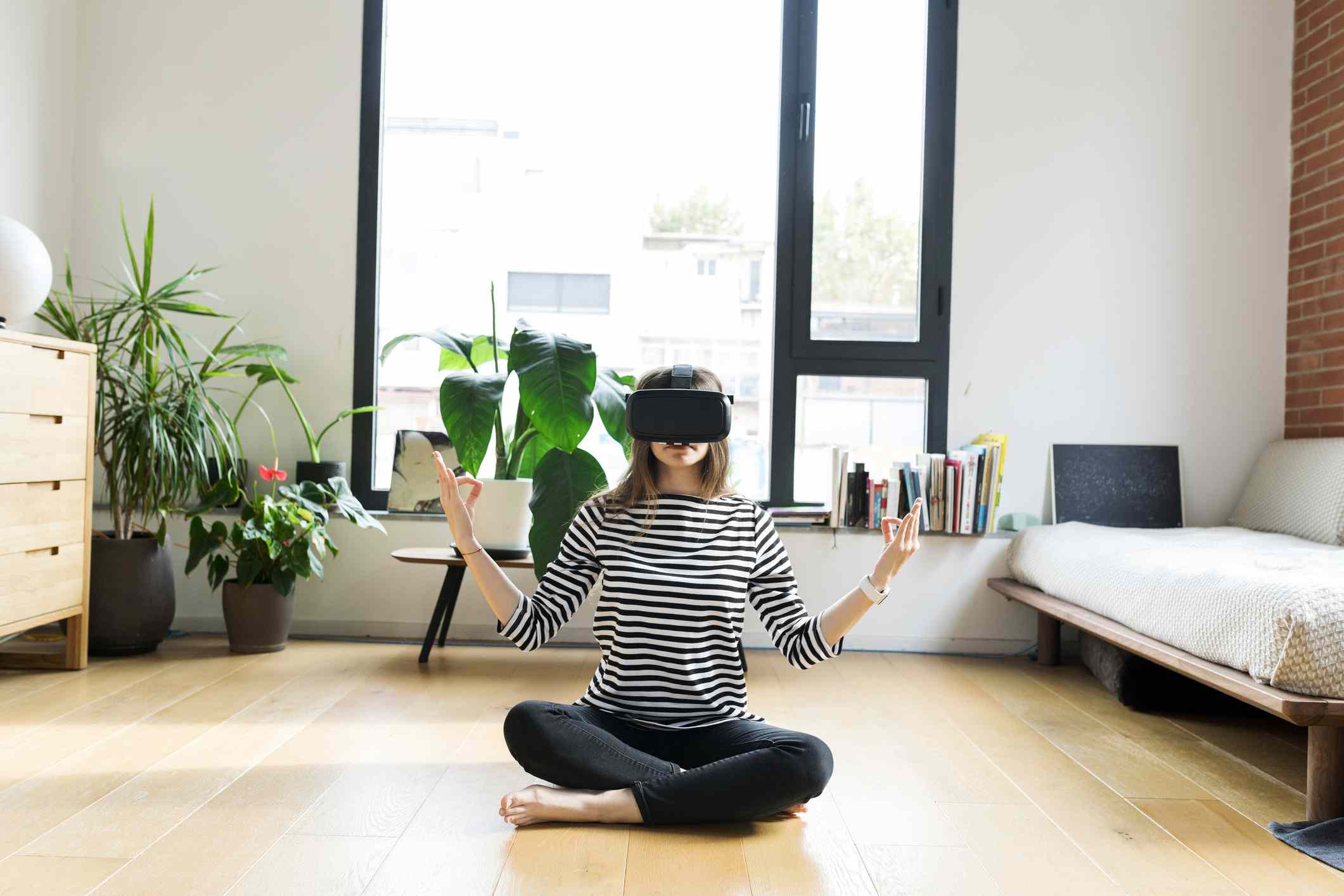 En ung person hemma som bär VR -glasögon och gör yoga.