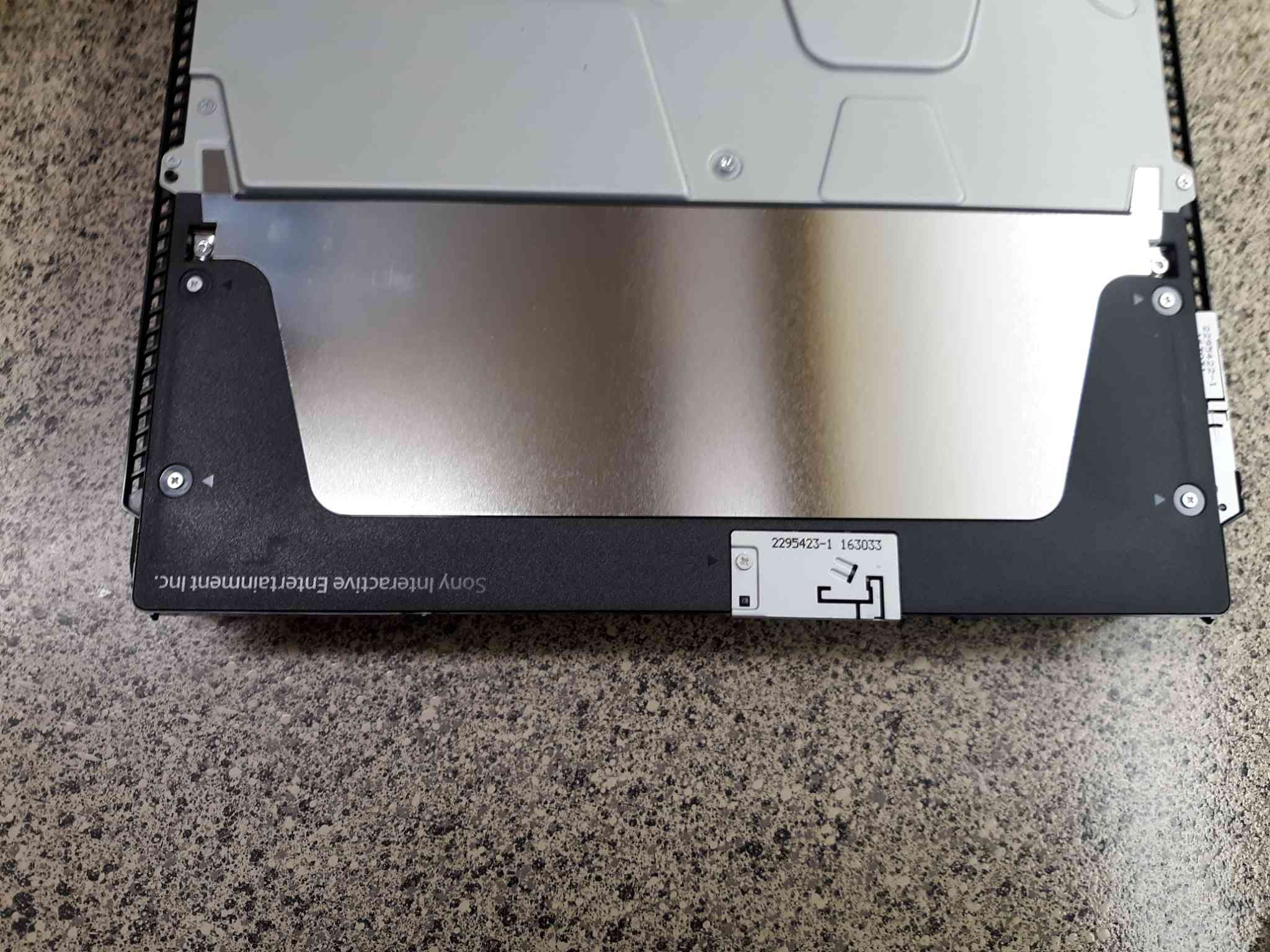 Använd en Phillips -skruvmejsel för att ta bort det svarta plastskyddet nära PS4 -konsolens bakre ände.