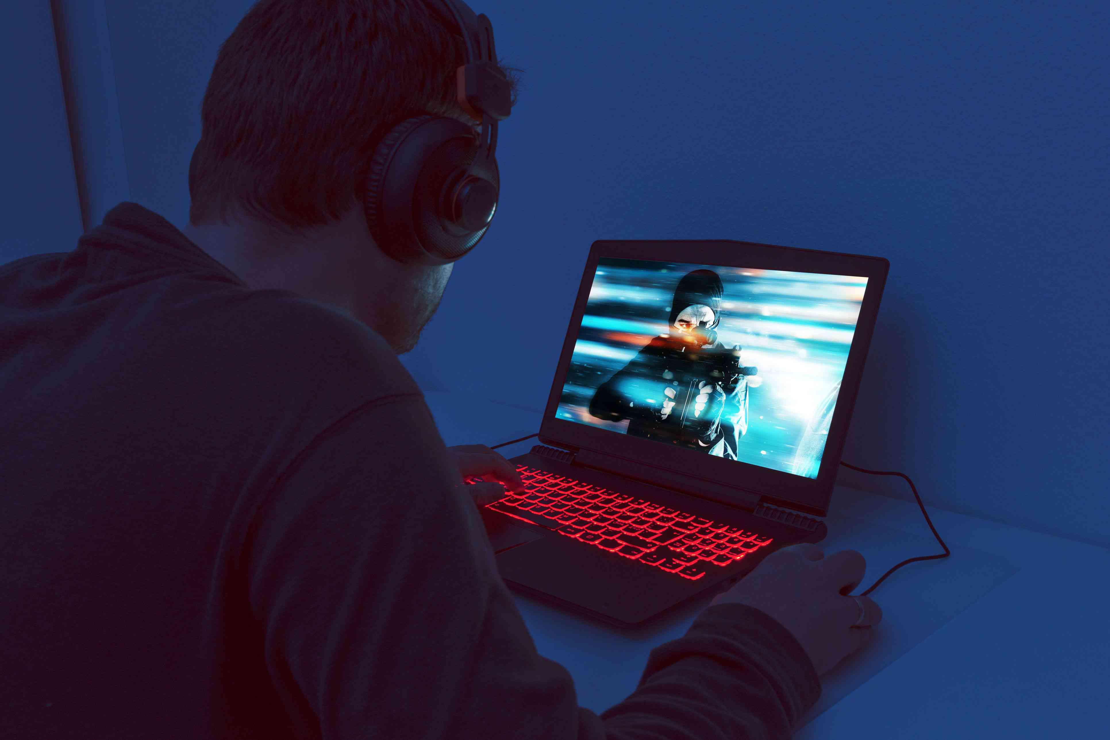 Mannen sitter ensam framför en bärbar dator och spelar ett tv -spel