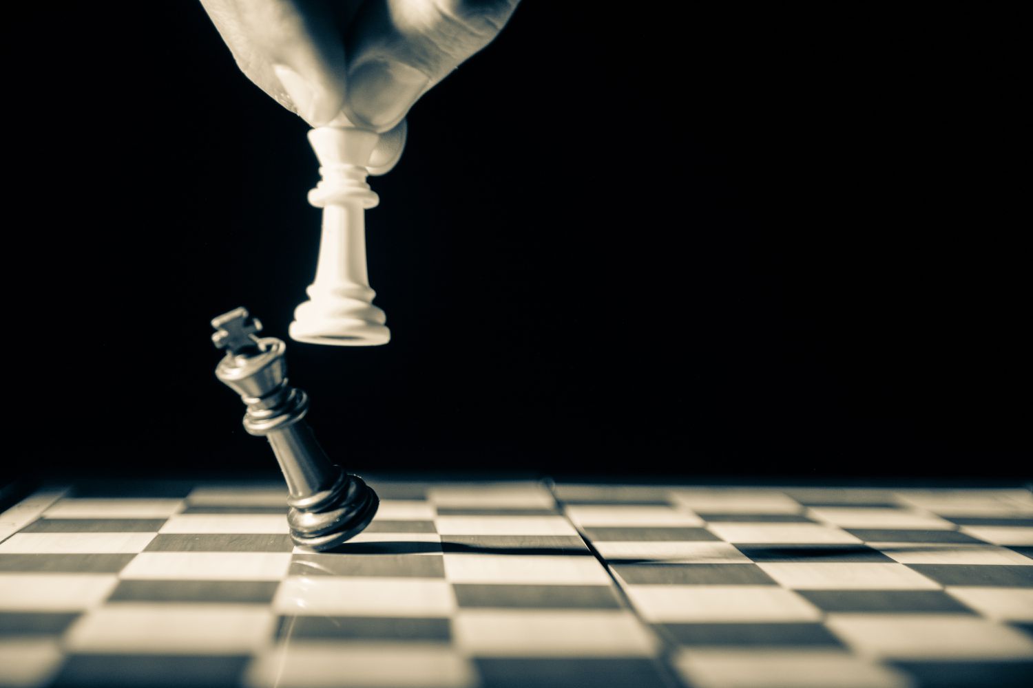 Närbild gråskalebild av en vit schackkung som tar ner en svart schackkung. 